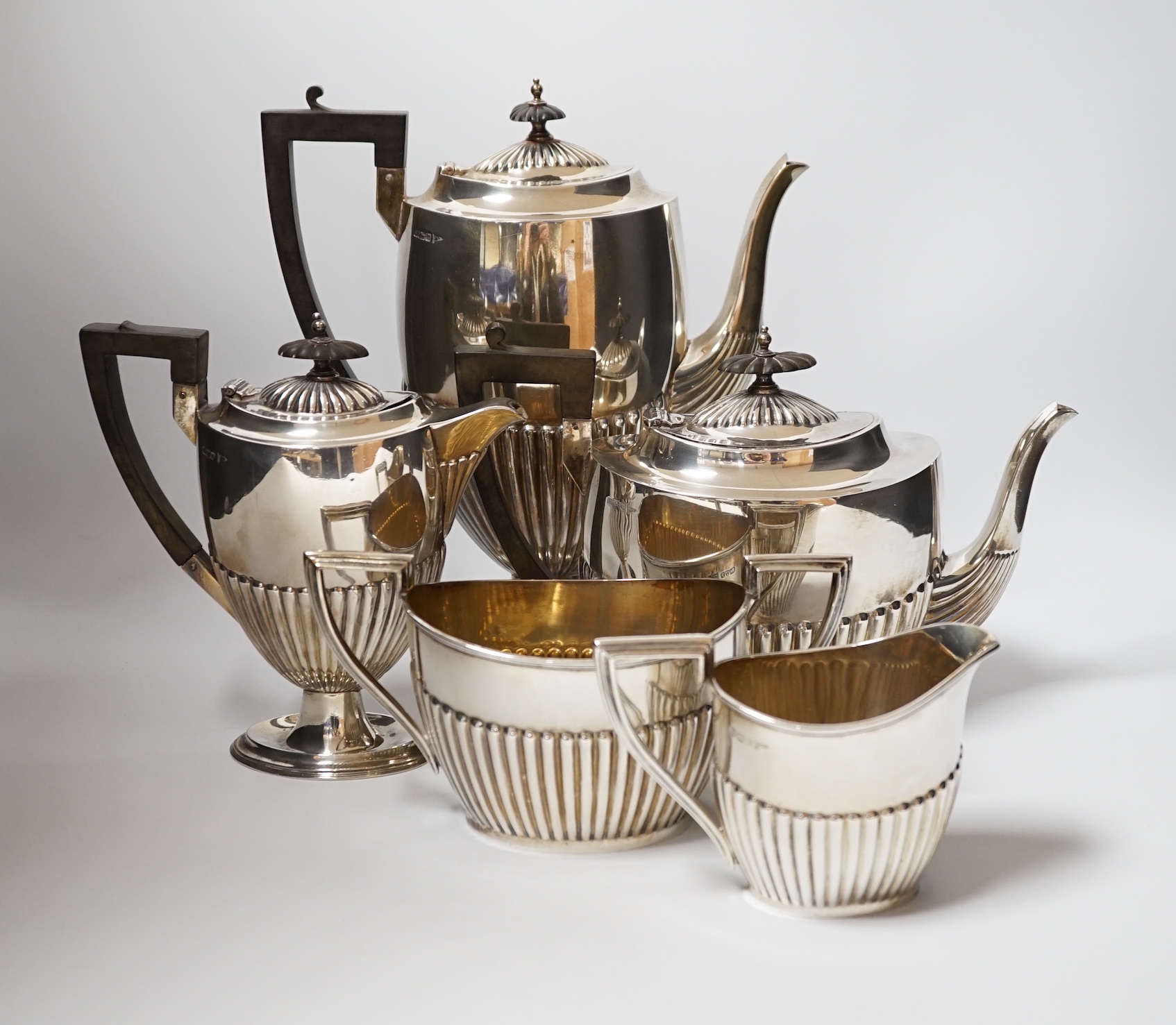An Edwardian matched demi fluted silver five piece tea and coffee service, by Walker & Hall, Chester, 1906 and Sheffield, 1907/1908, the coffee pot and hot water jug with pedestal foot, gross weight 79.3oz.